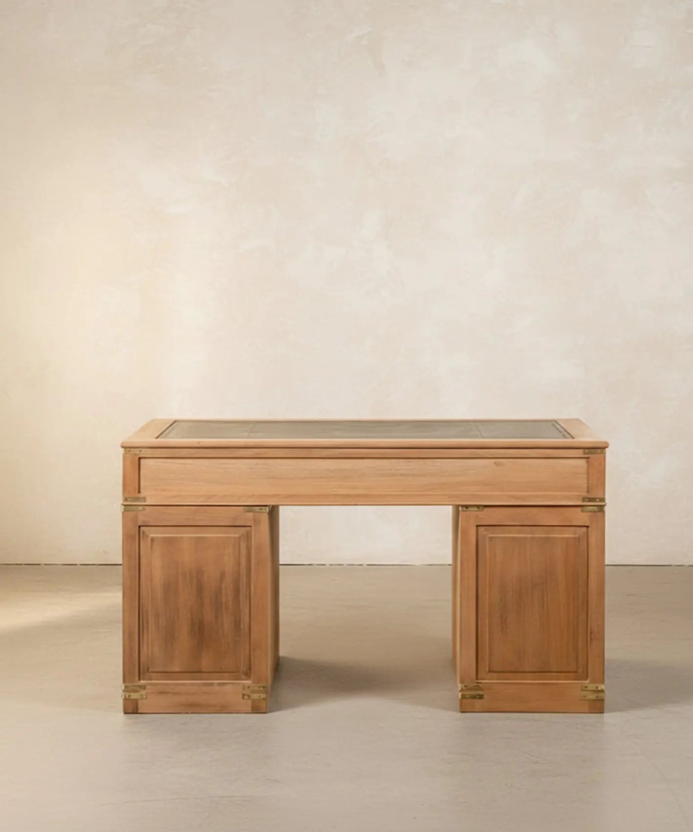 Escritorio de campaña inglés de madera clara con ocho cajones y sobre de cuero verde en ambiente de estudio.