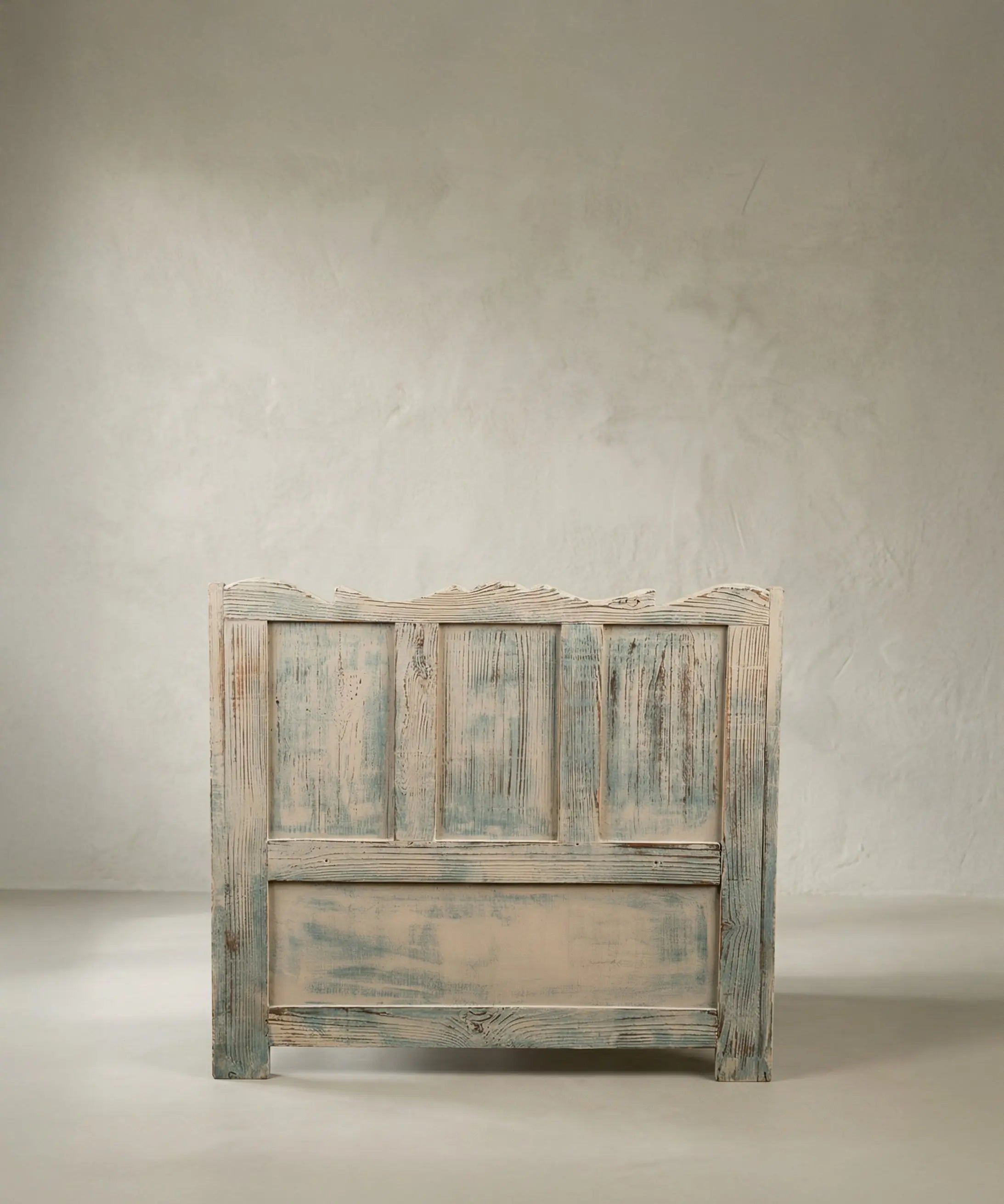 Parte trasera de banco rústico de madera panelada con acabado de pintura desgastada.