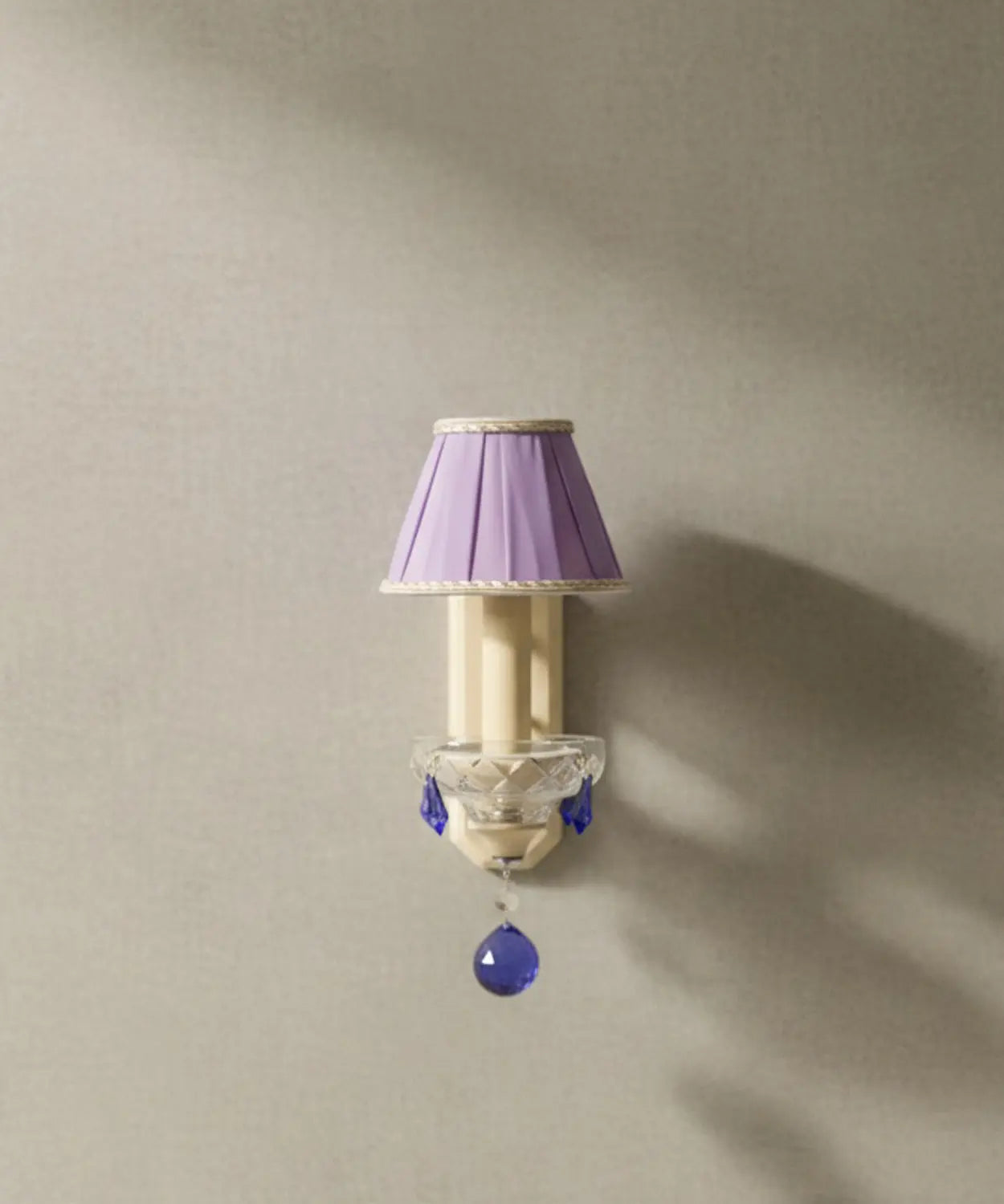 Vista frontal del aplique mostrando la pantalla plisada malva y la esfera de cristal azul central sobre fondo neutro.