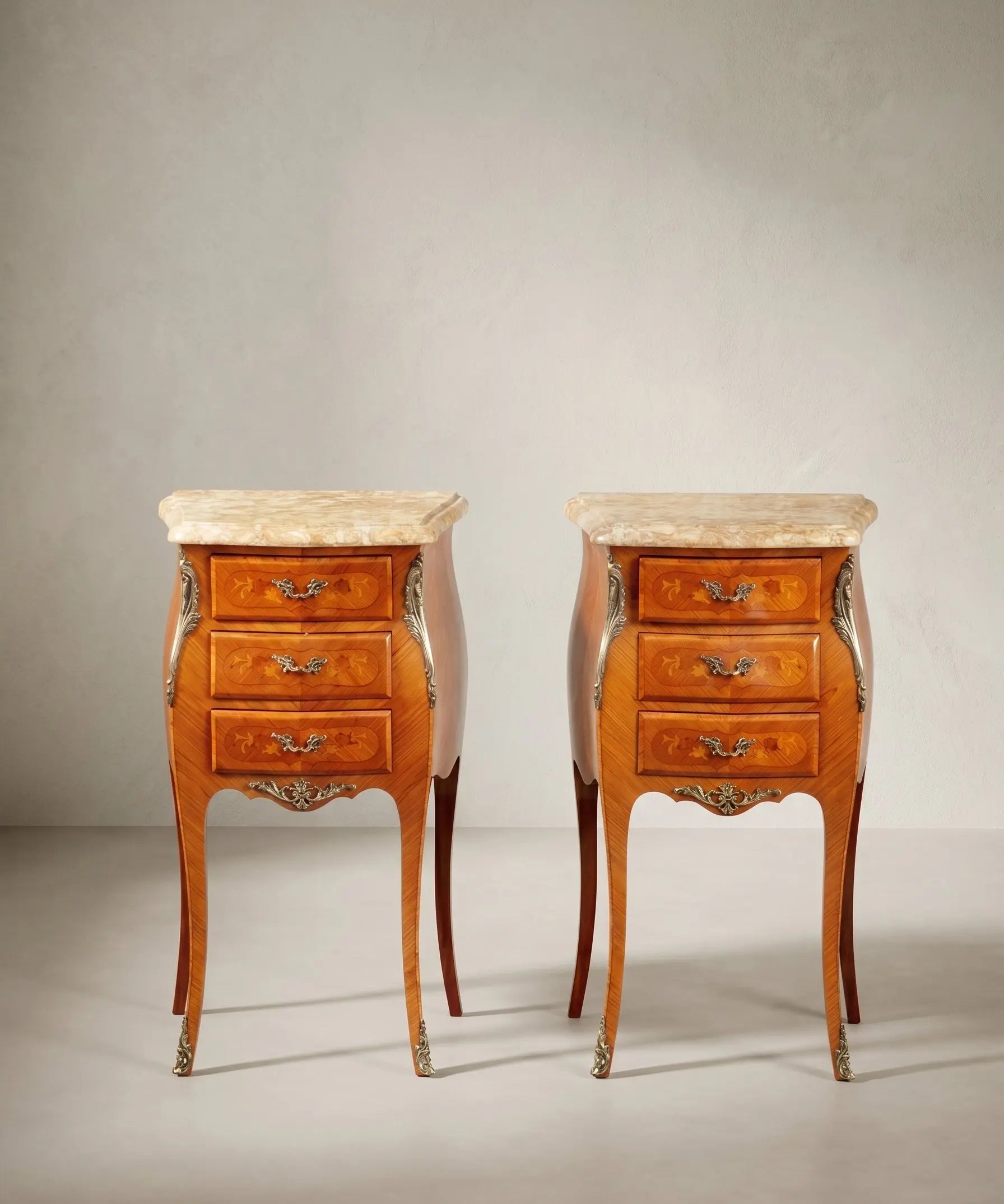 Pareja de mesitas de noche vintage de planta arriñonada con tres cajones y marquetería floral.