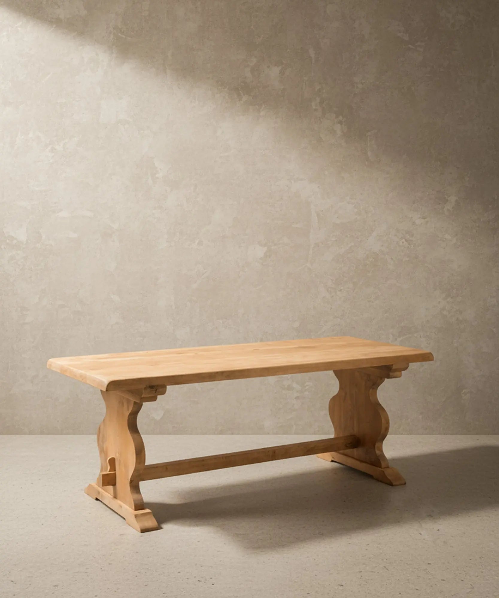 Vista angular de la mesa de comedor estilo refectorio mostrando la profundidad del tablero y el diseño tallado de las patas de lira.