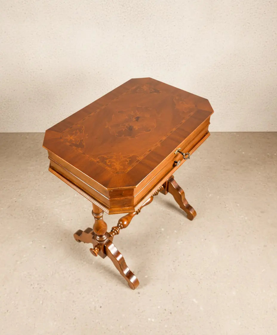 Mesa de costura antigua de madera noble con marquetería floral en la tapa y patas torneadas.