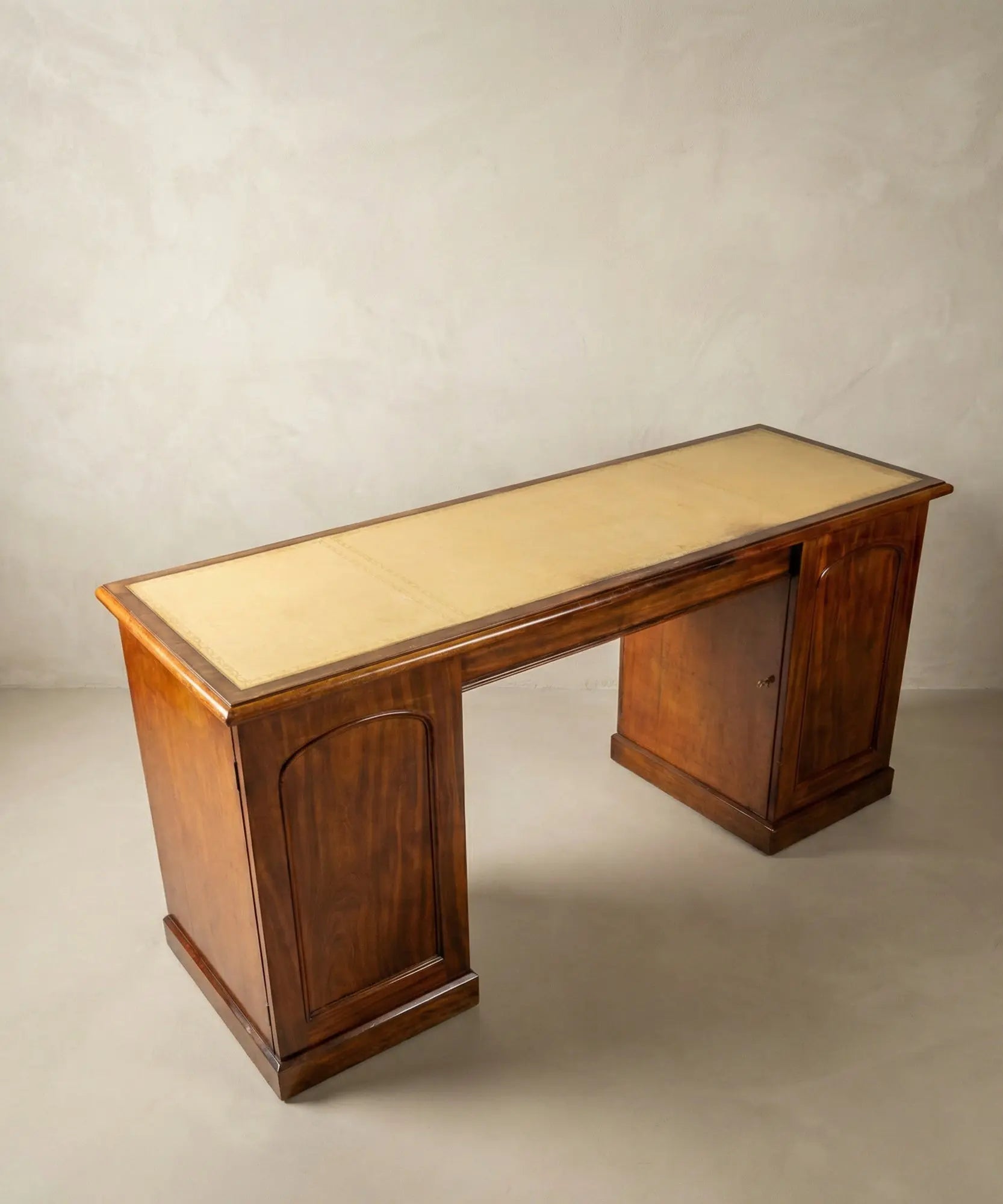 Vista superior de escritorio antiguo mostrando el tapete de cuero crema con grabados dorados.