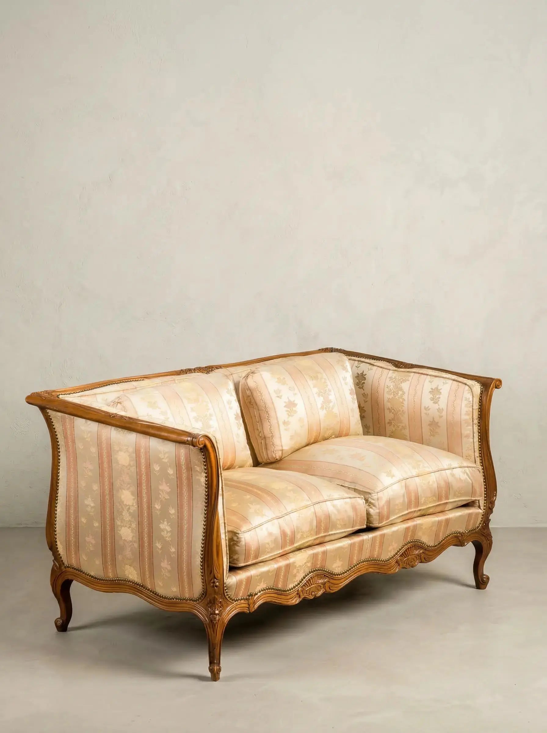 Vista diagonal de sofá clásico afrancesado mostrando patas curvas de madera y cojines mullidos.