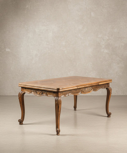 Mesa de comedor estilo Luis XV en madera noble con patas cabriolé frente a fondo blanco.