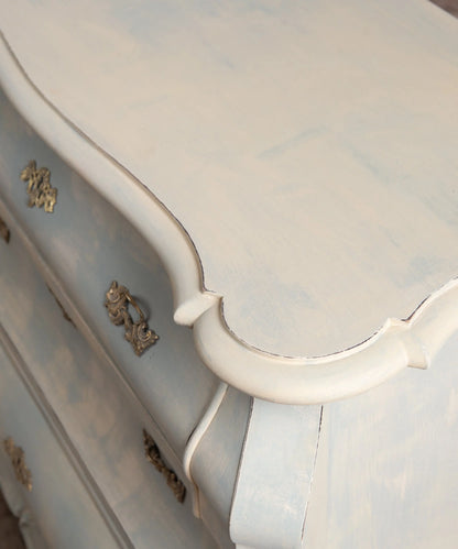 Primer plano del acabado decapé difuminado efecto nube en azul empolvado sobre cómoda vintage.