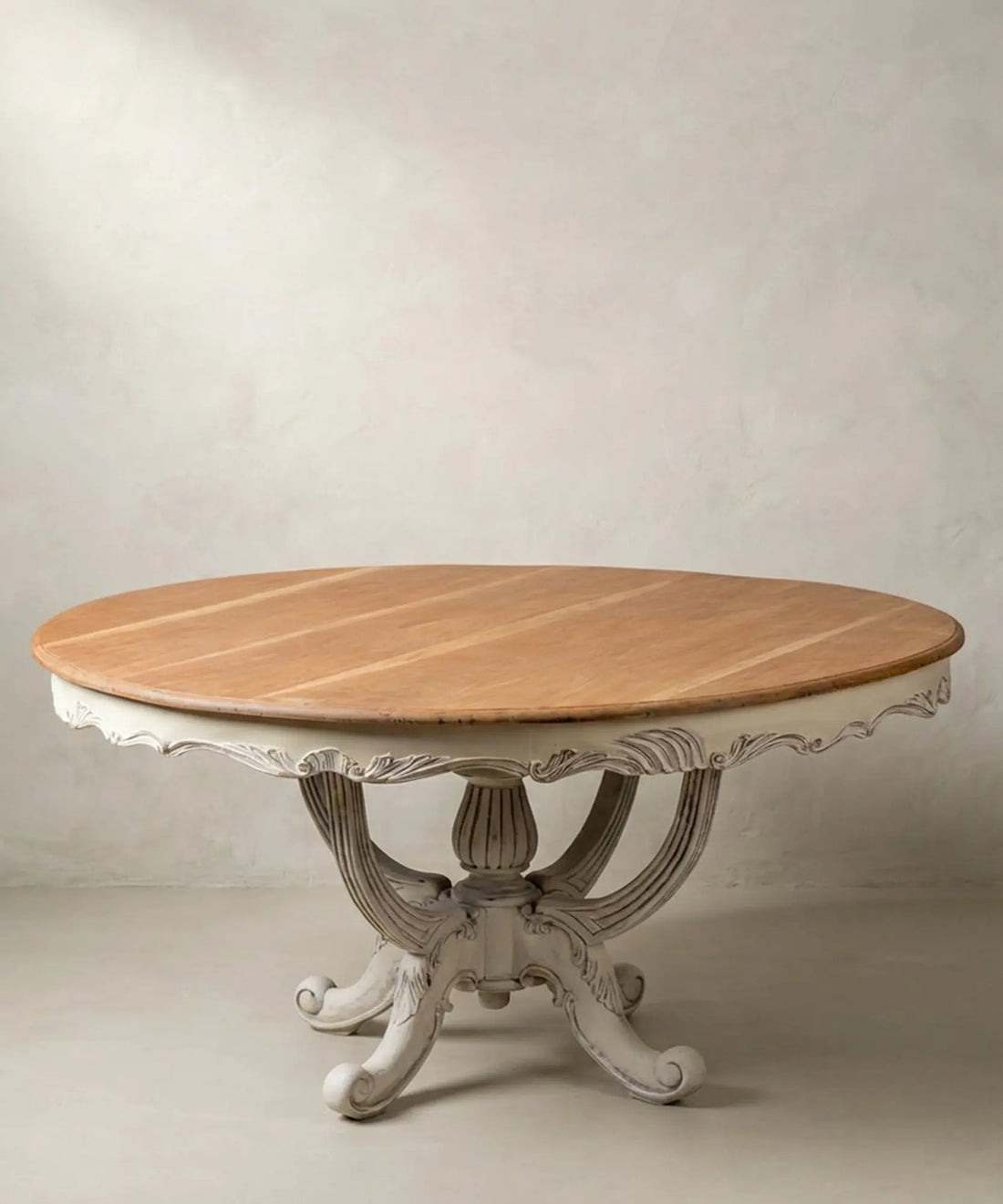 Mesa de comedor redonda antigua restaurada con tablero de caoba natural y base blanca tallada.