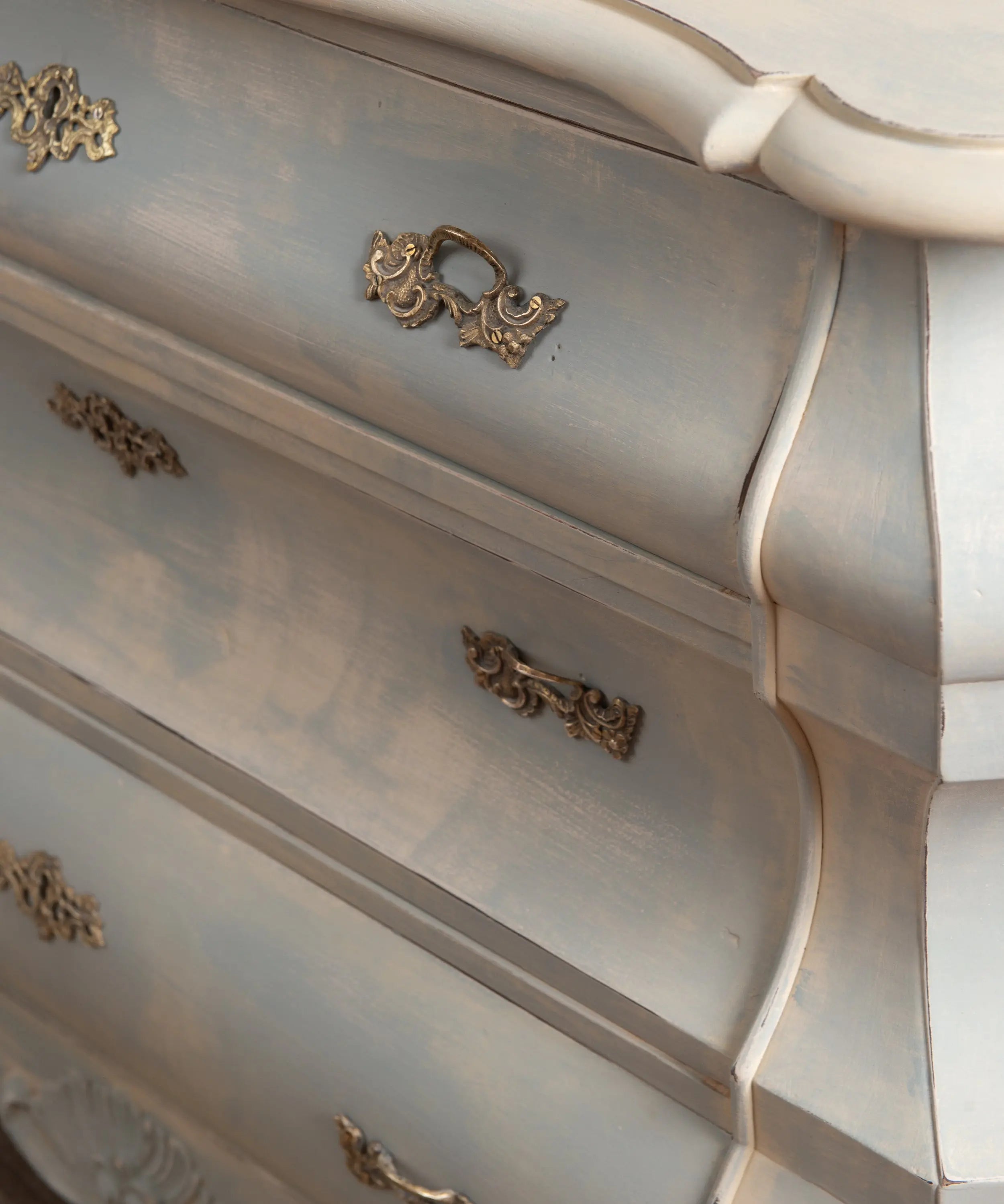 Primer plano del acabado decapé difuminado efecto nube en azul empolvado sobre cómoda vintage.