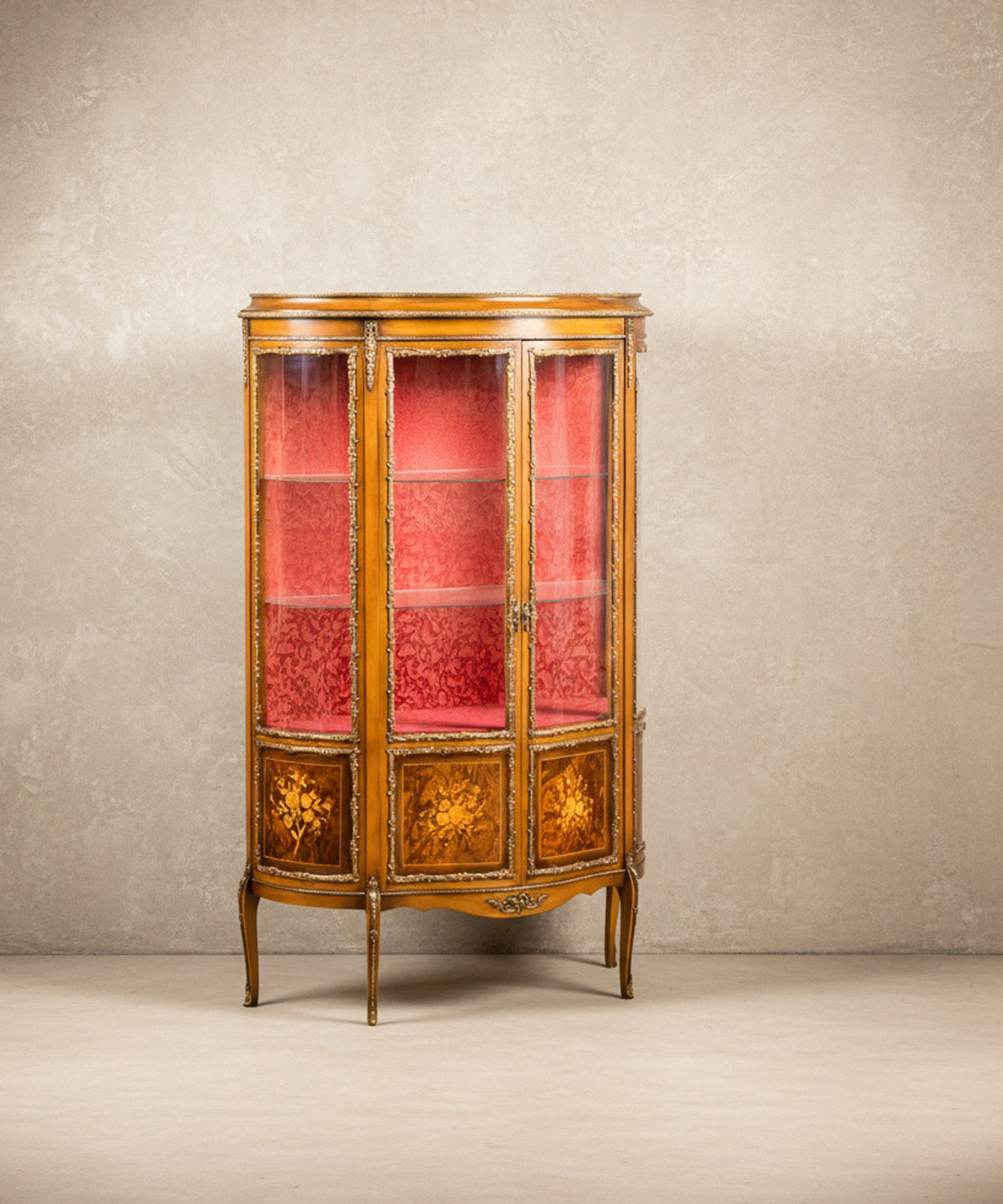  Vista lateral de vitrina antigua con cristales curvos y aplicaciones de bronce.