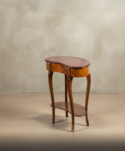 Perspectiva lateral que resalta la curva elegante de las patas y la balda inferior de la mesa auxiliar.