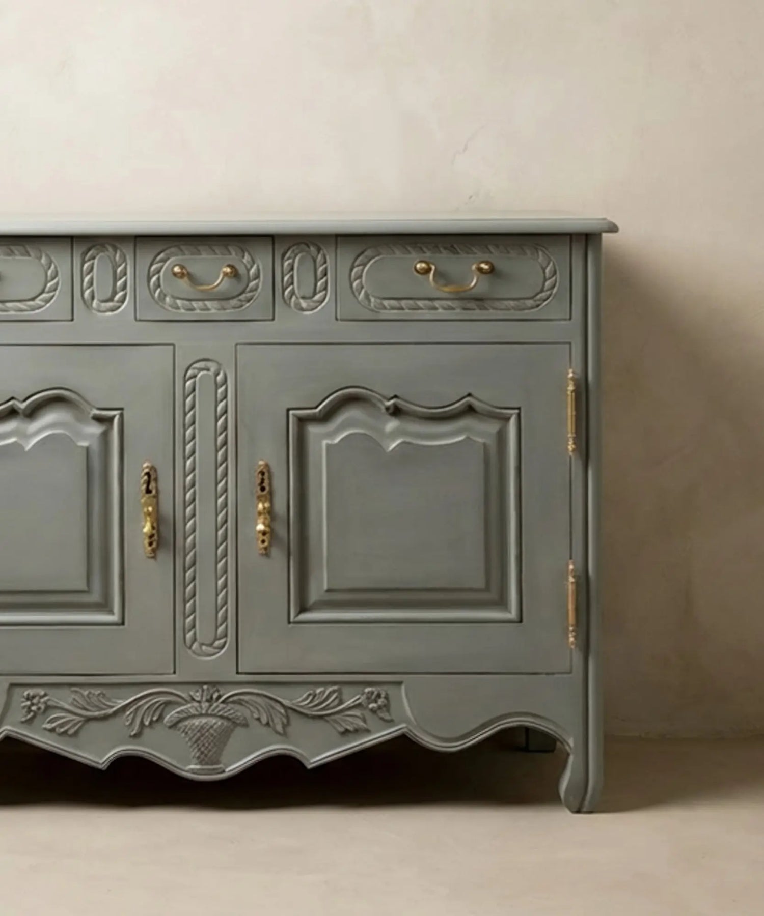 Primer plano de la talla artesanal de cesta floral en el faldón inferior del mueble.