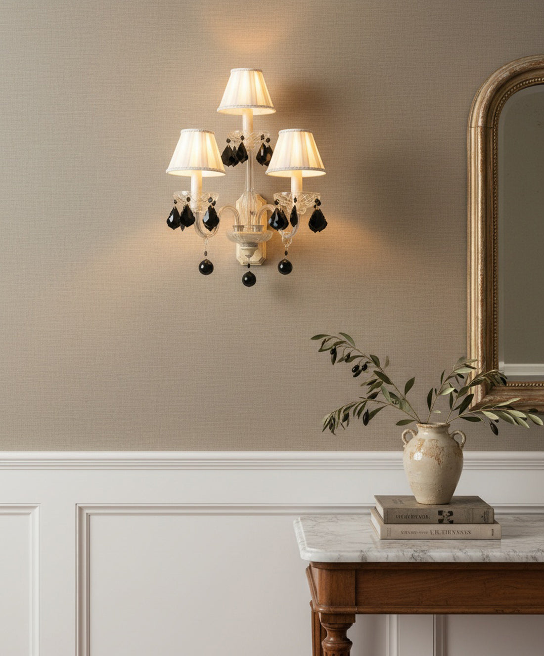 Aplique de pared vintage de 3 luces con brazos de cristal y lágrimas negras colgantes sobre pared beige.