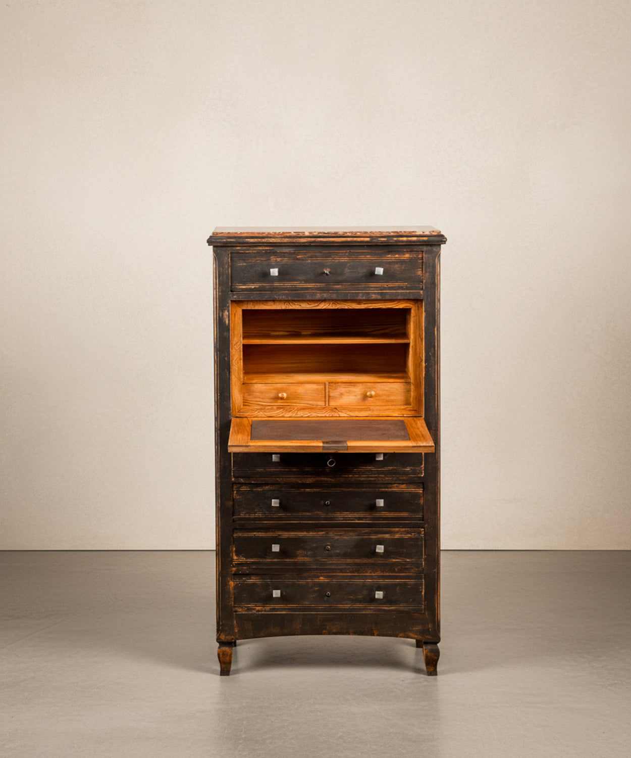 Primer plano del escritorio interior del secreter, estantes y cajoncitos de madera natural pulida.