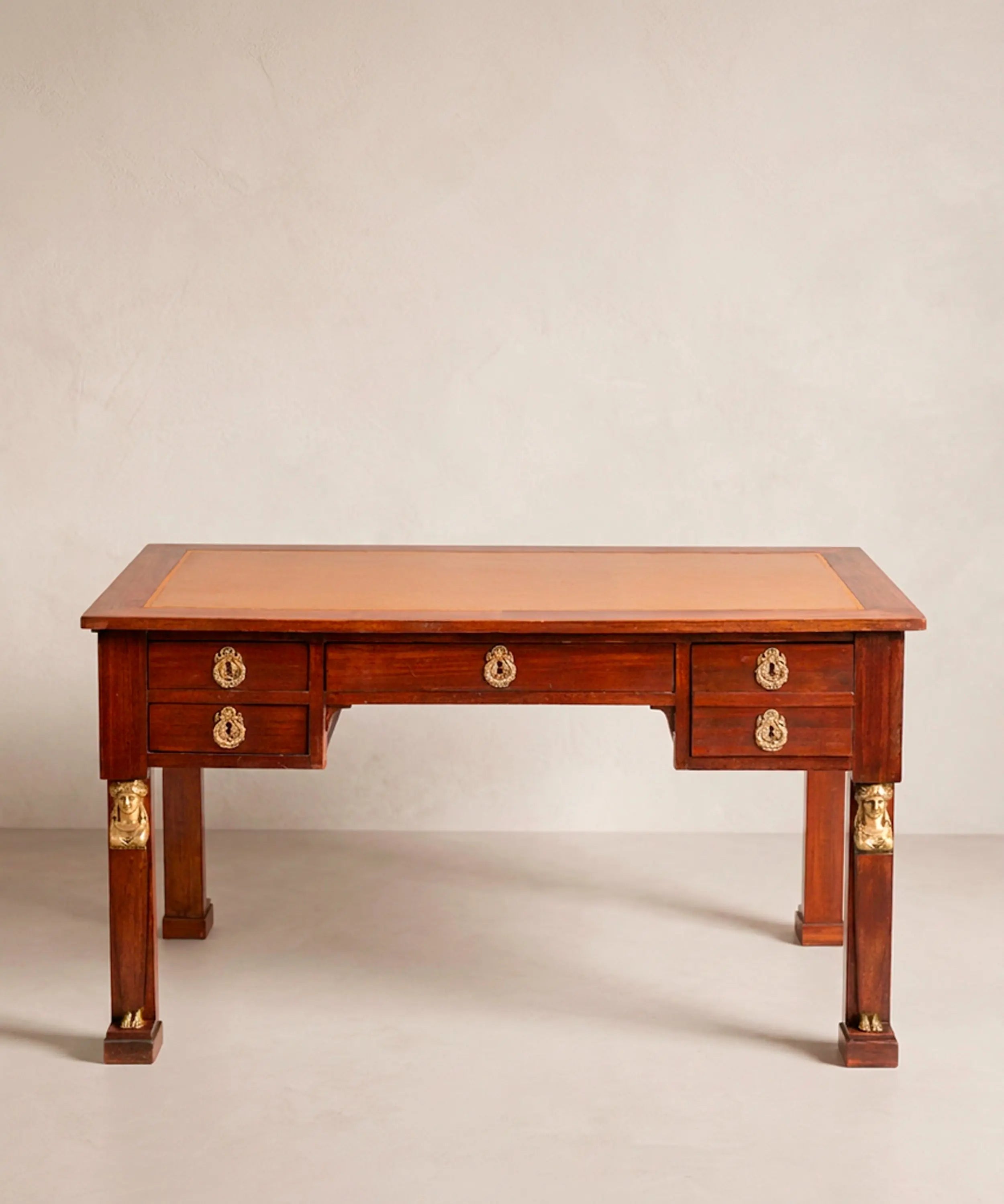 Elegante despacho clásico con escritorio antiguo estilo Imperio de caoba en el centro de la habitación.