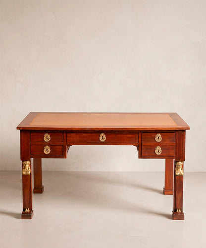 Elegante despacho clásico con escritorio antiguo estilo Imperio de caoba en el centro de la habitación.