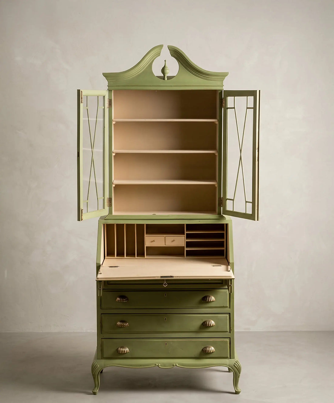 Vitrina secreter vintage verde con el escritorio abatible abierto mostrando su interior beige.