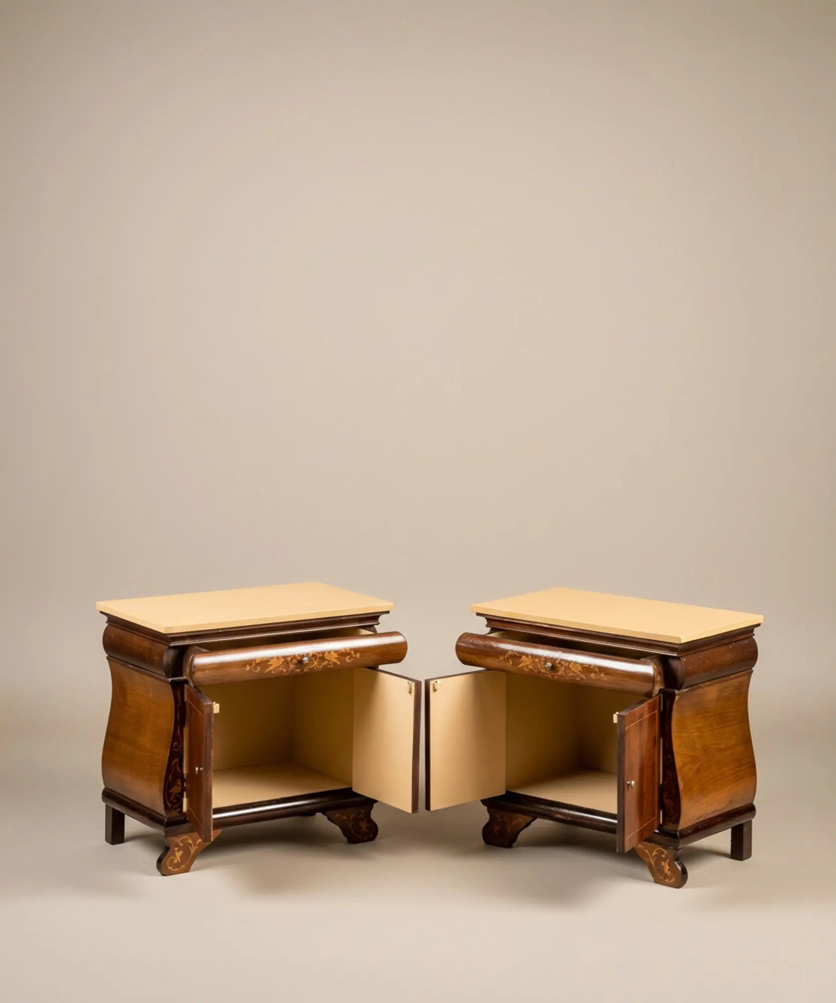 Pareja de mesitas de noche vintage con marquetería de aves y puertas abiertas frente a mural sepia.