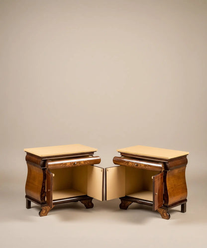 Pareja de mesitas de noche vintage con marquetería de aves y puertas abiertas frente a mural sepia.