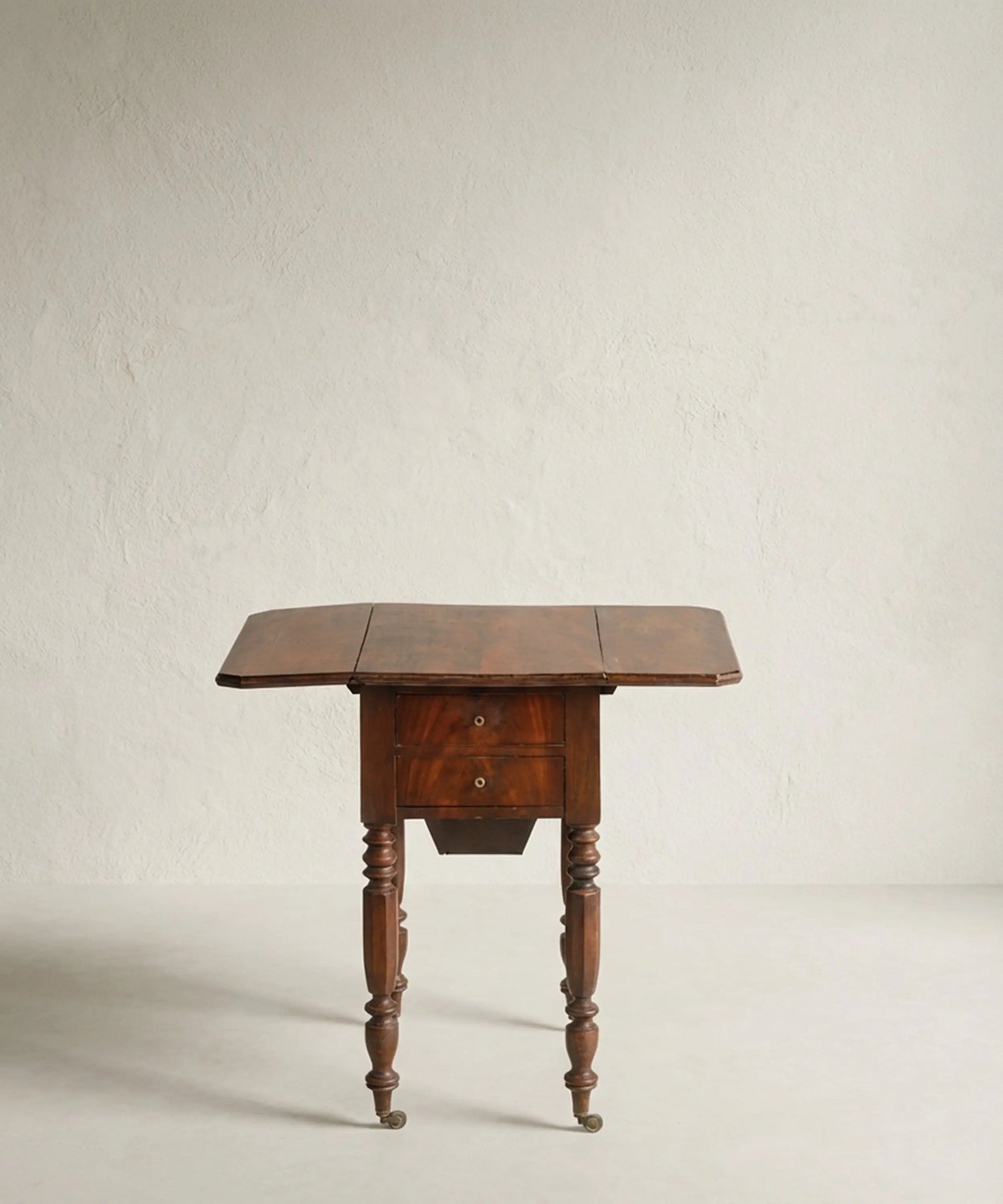 Mesa auxiliar de madera de caoba con alas laterales abatibles desplegadas.