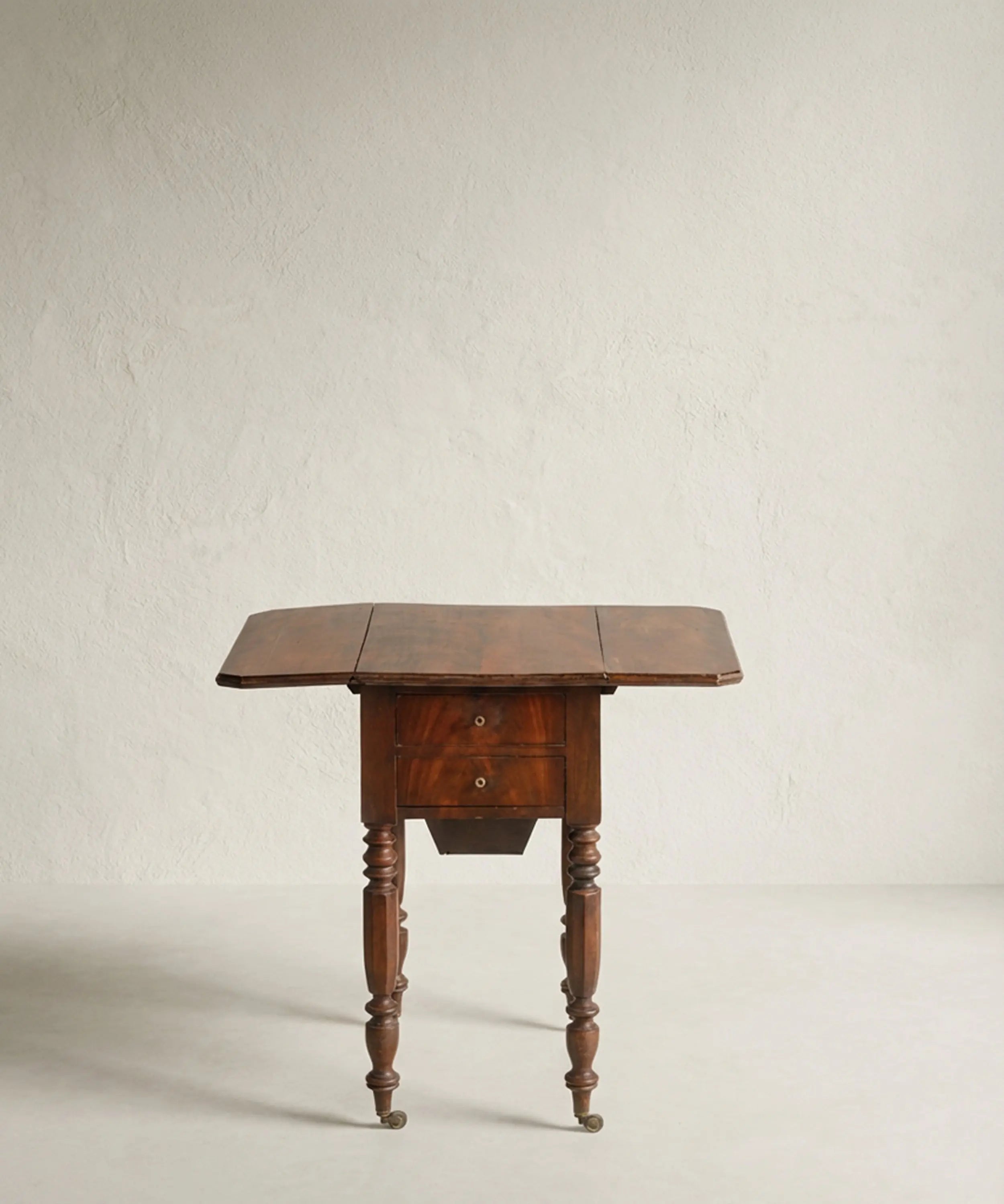 Mesa auxiliar de madera de caoba con alas laterales abatibles desplegadas.