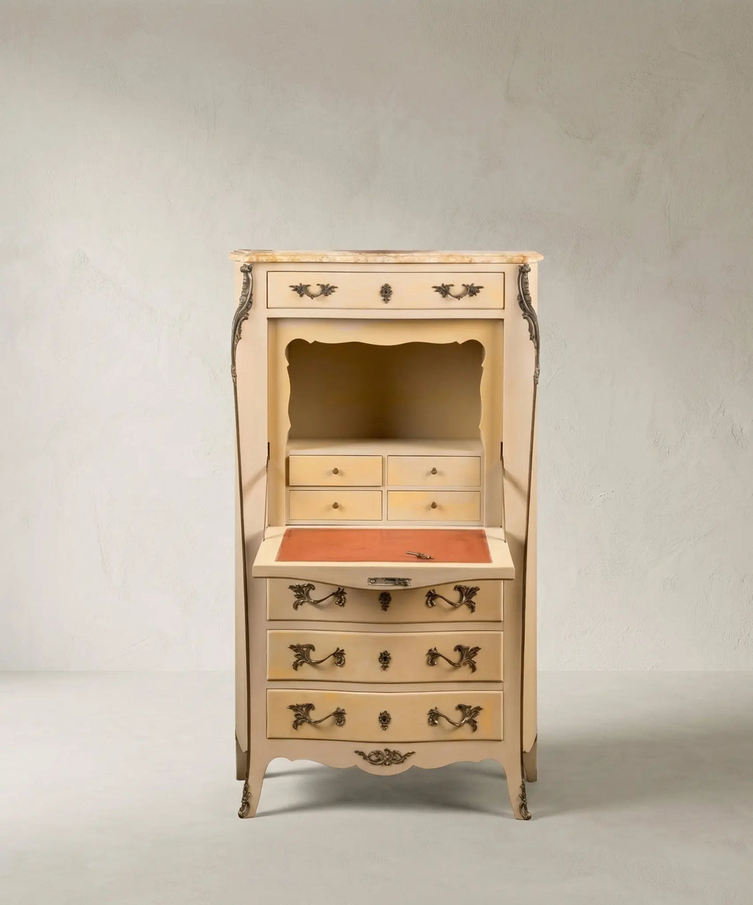 Interior de escritorio secreter antiguo con puerta abatible, tapete de escritura y cajones pequeños.