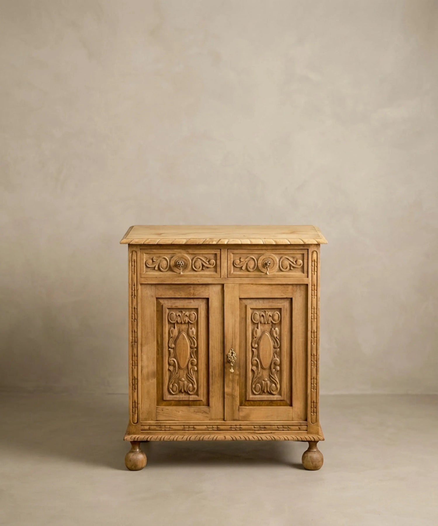 Pequeño mueble aparador de madera maciza estilo renacimiento con patas de bola y puertas talladas.