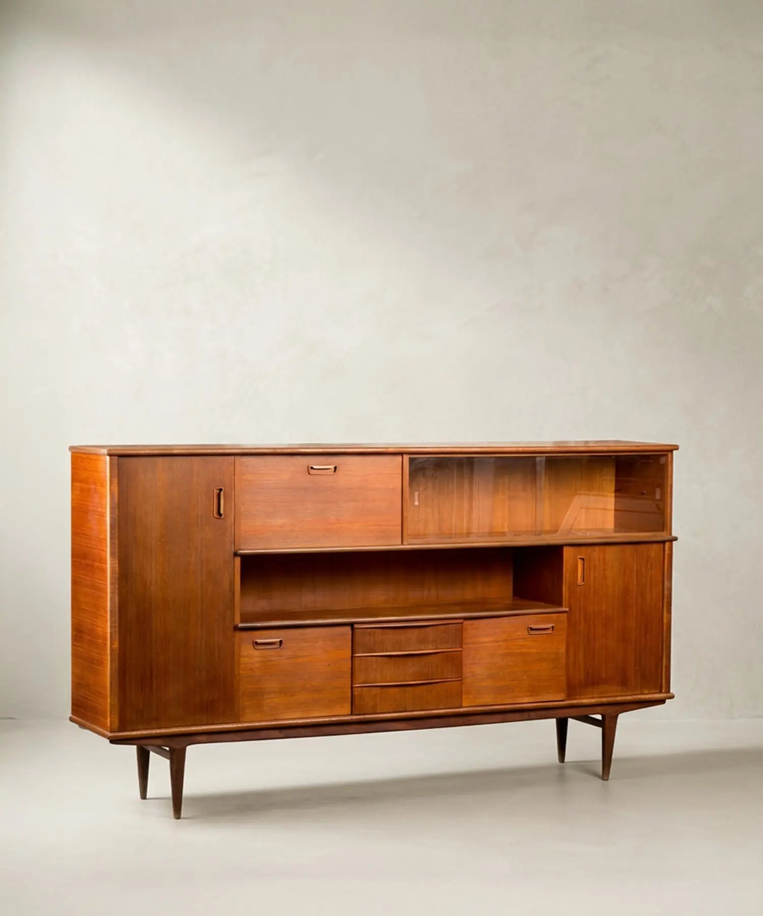 Aparador Mid-Century Modern de teca con puertas y vitrina frontal sobre fondo neutro.