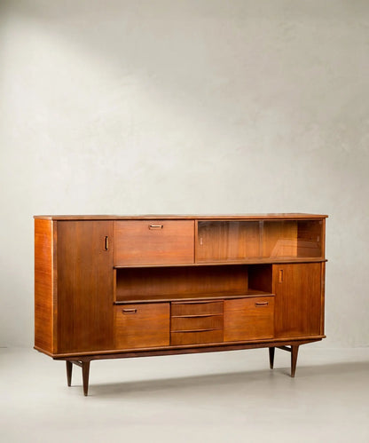 Aparador Mid-Century Modern de teca con puertas y vitrina frontal sobre fondo neutro.