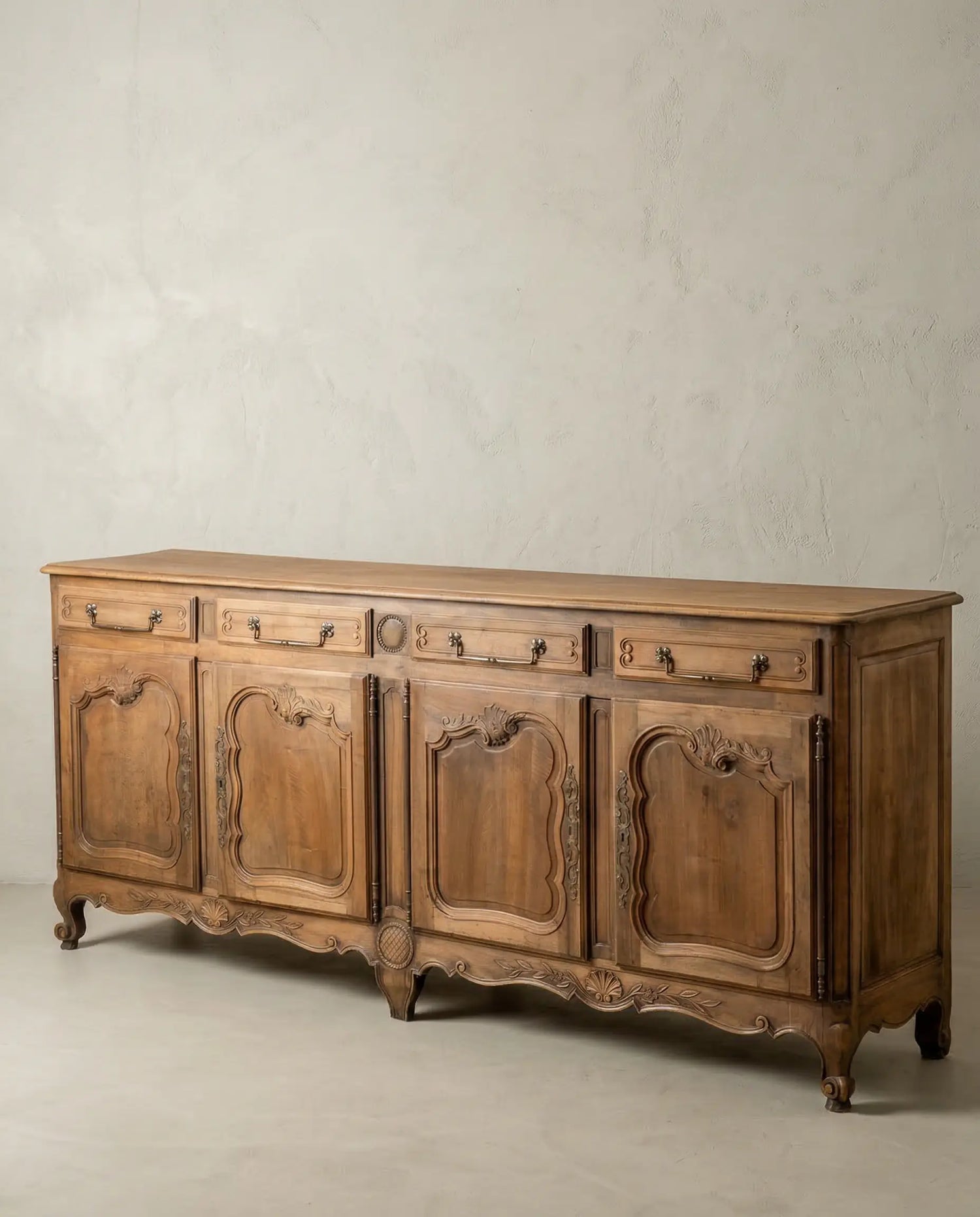 Vista diagonal de mueble enfilade vintage con patas curvas y madera cruda.