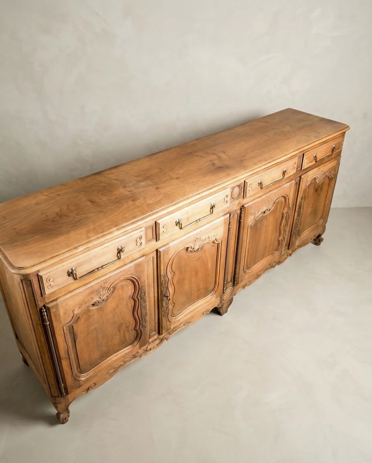 Vista diagonal de mueble enfilade vintage con patas curvas y madera cruda.