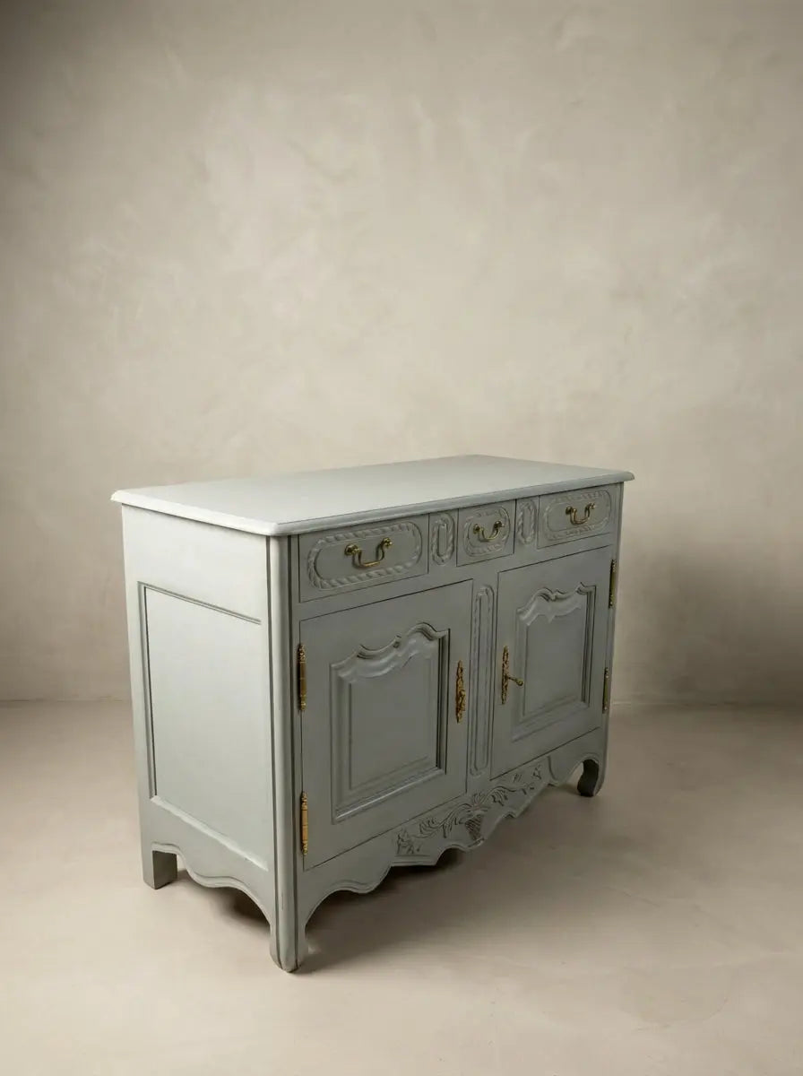 Aparador de estilo provenzal francés en color azul bruma con tallas florales y herrajes de latón.