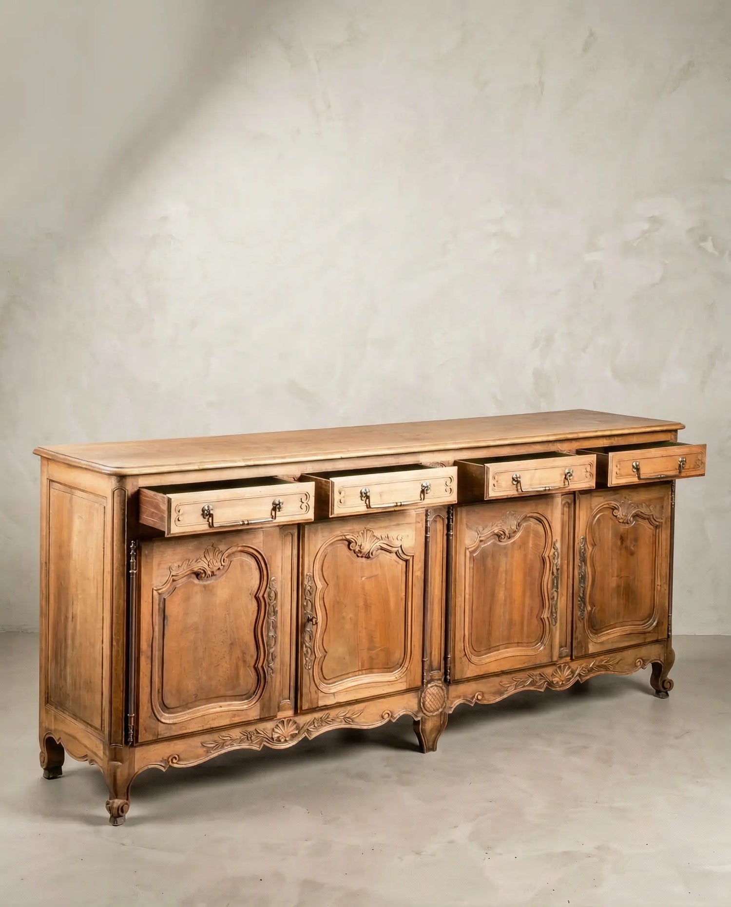 Vista diagonal de mueble enfilade vintage con patas curvas y madera cruda.