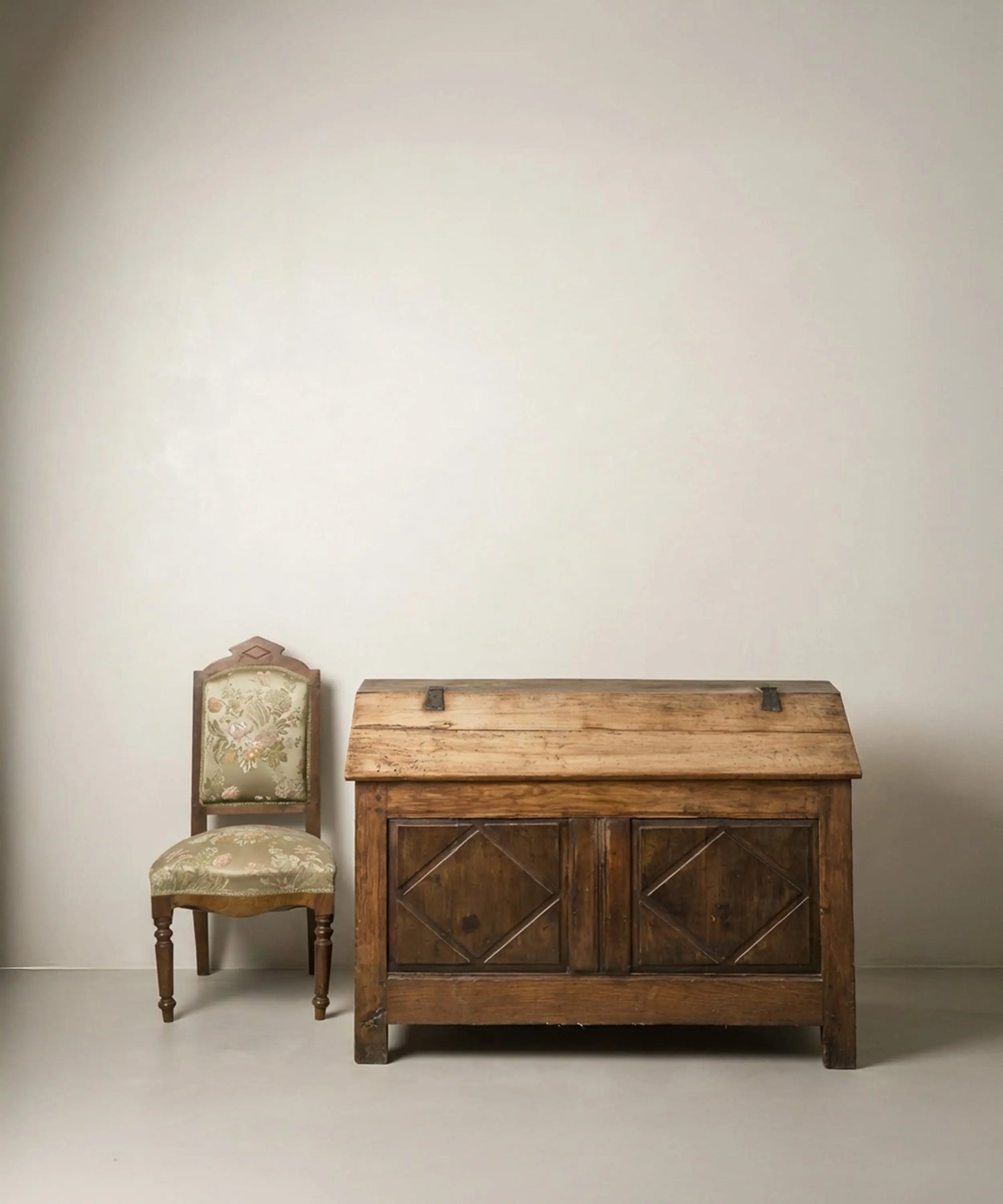 Vista frontal en ángulo de arca  antigua de madera con tapa inclinada y tallas de rombos.