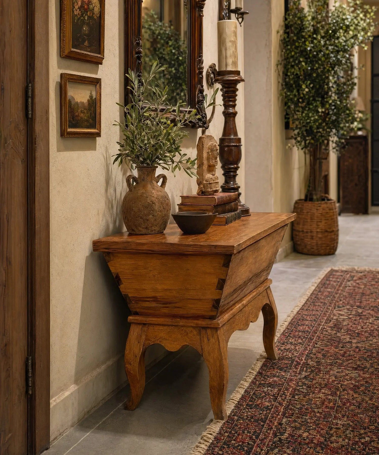 Mesa antigua tipo artesa de madera maciza con patas curvas y tapa plana estilo rústico en pasillo de piso actual