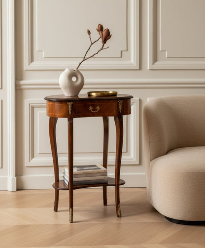 Mesa auxiliar decorada con libros y flores en un ambiente de biblioteca clásica con estanterías y cortinas.