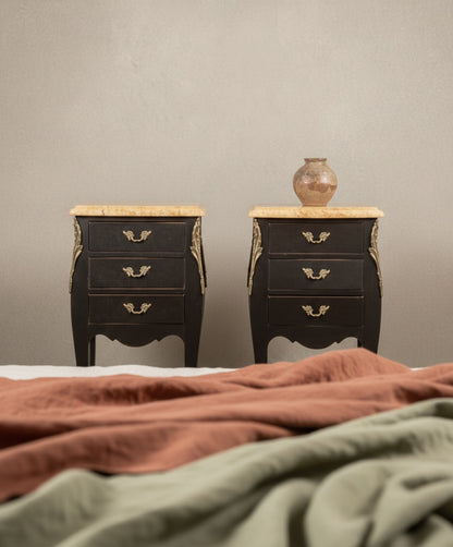 Pareja de mesillas de noche francesas estilo Luis XV en color negro mate con tres cajones y sobres de mármol.