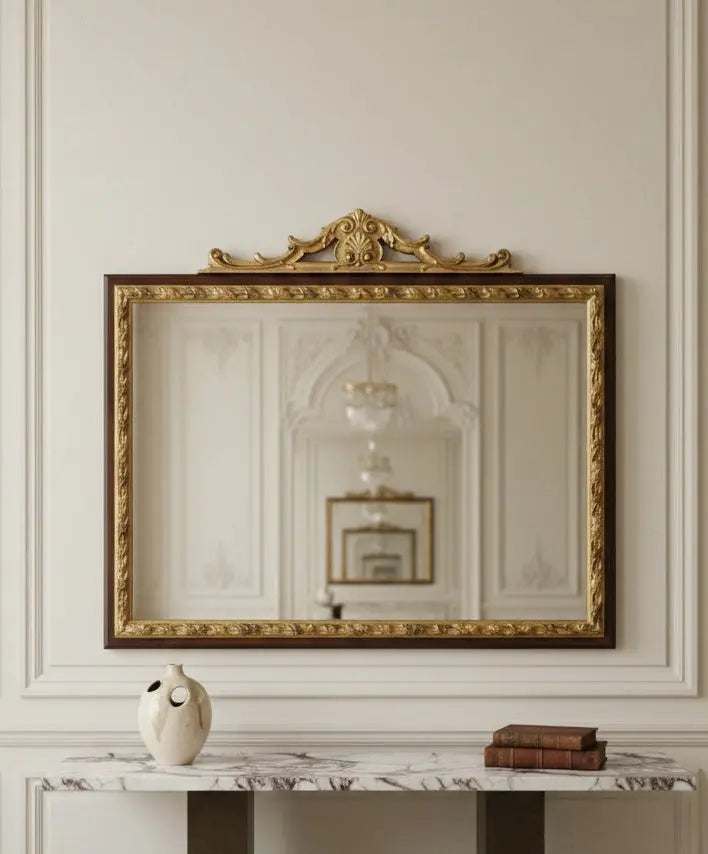 Espejo antiguo dorado decorando un recibidor moderno sobre consola de mármol minimalista.