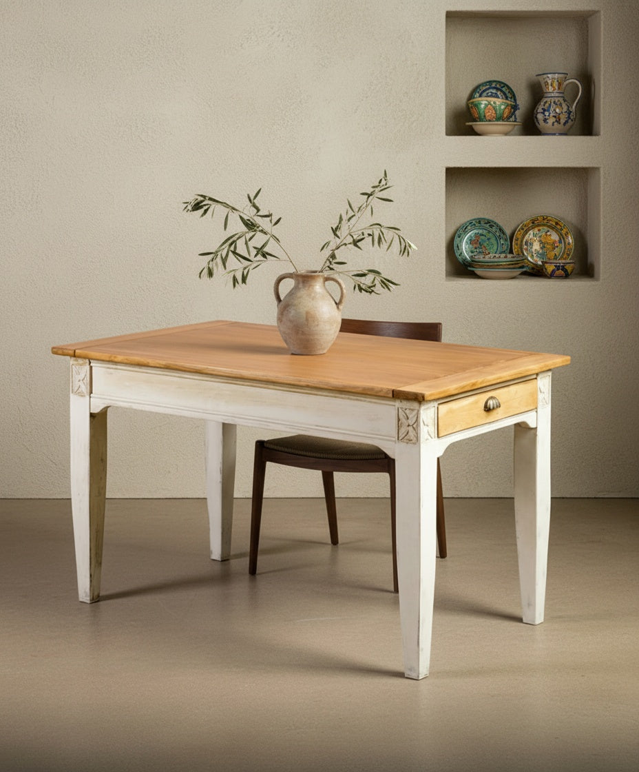 Mesa L’Atelier ambientada en un comedor rústico con jarrón cerámico y luz natural.