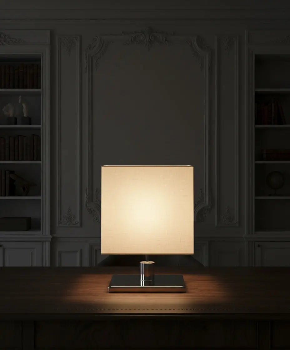 Lámpara Épure encendida en ambiente de biblioteca clásica, mostrando la calidez del haz de luz sobre madera.