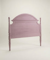 Vista en perspectiva del cabecero rosa mostrando el grosor de los postes y las molduras decorativas