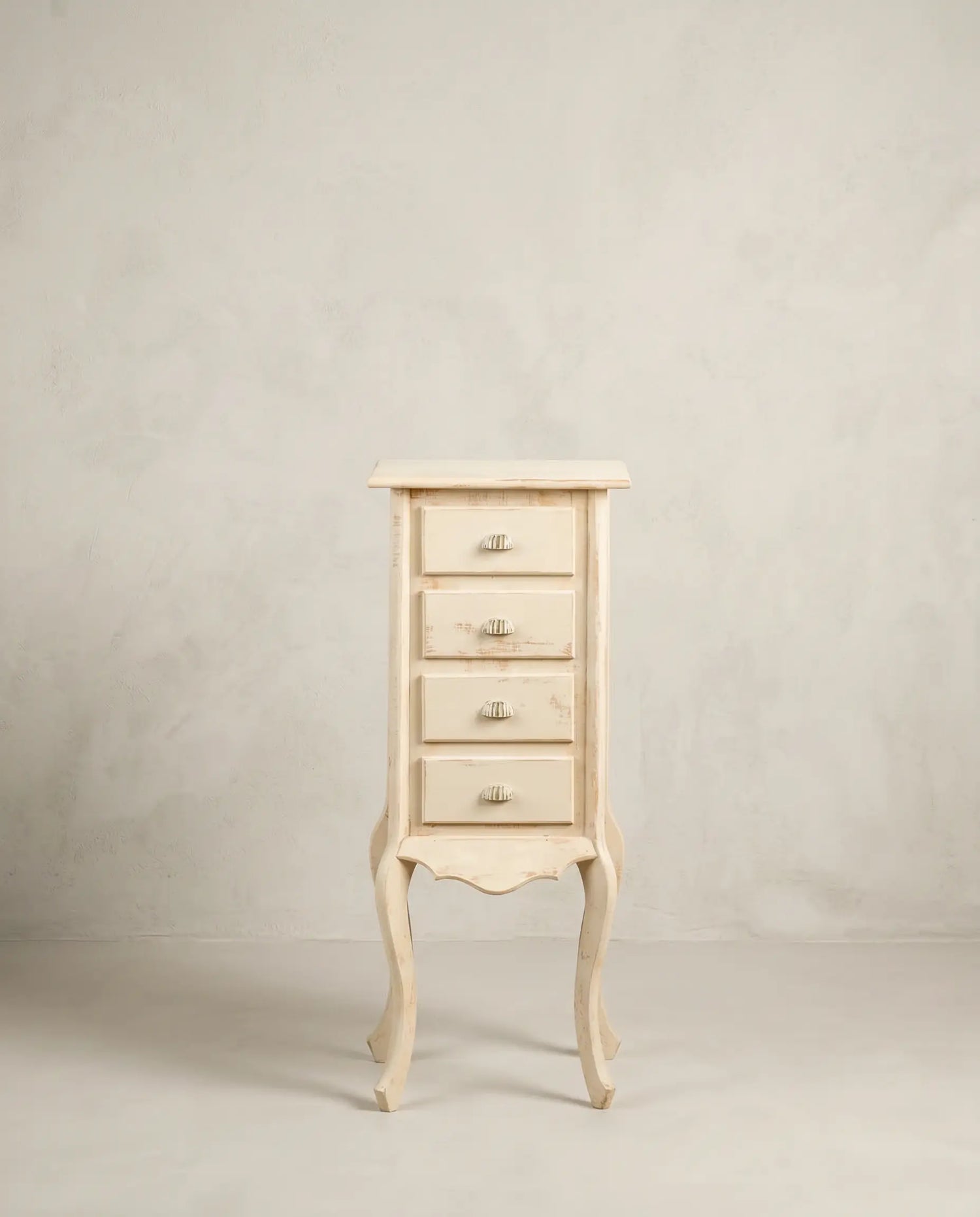 Cajonera auxiliar vintage estrecha de color blanco viejo desgastado con patas curvas.