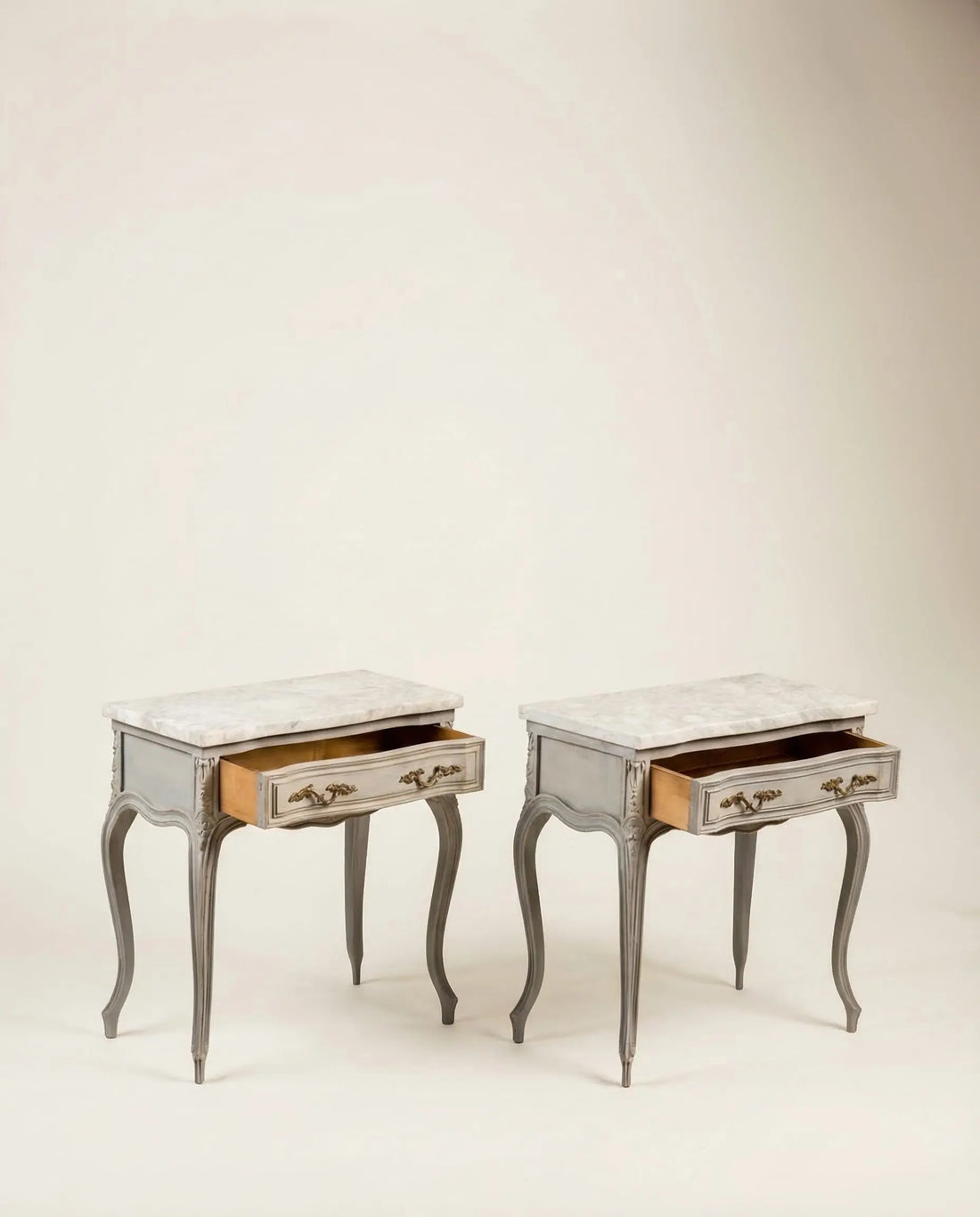 Mesitas auxiliares clásicas restauradas con los cajones abiertos mostrando su interior.