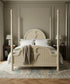 Cama con dosel de madera color crema Héritage vestida con ropa de cama neutra en dormitorio de lujo.