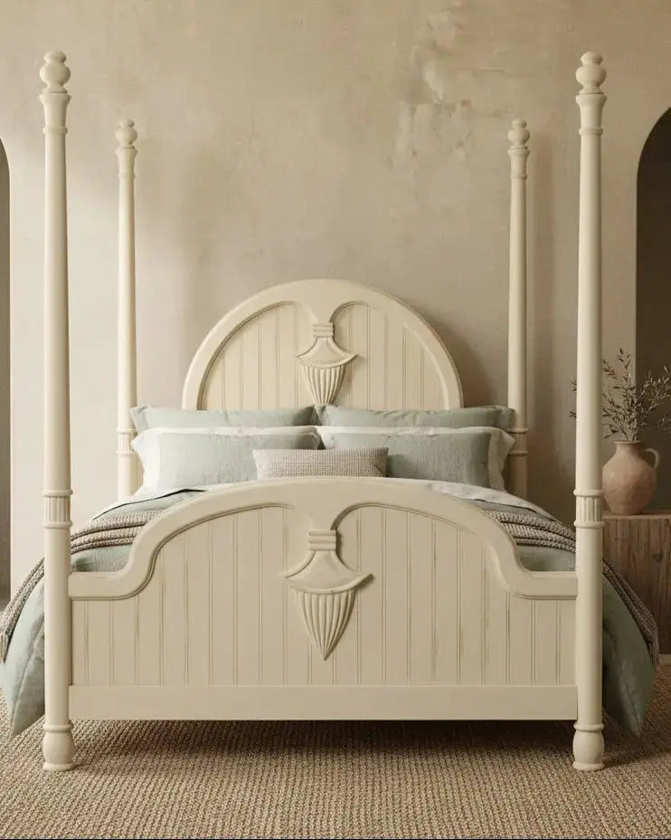 Cama con dosel de madera color crema  vestida con ropa de cama neutra en dormitorio de lujo.