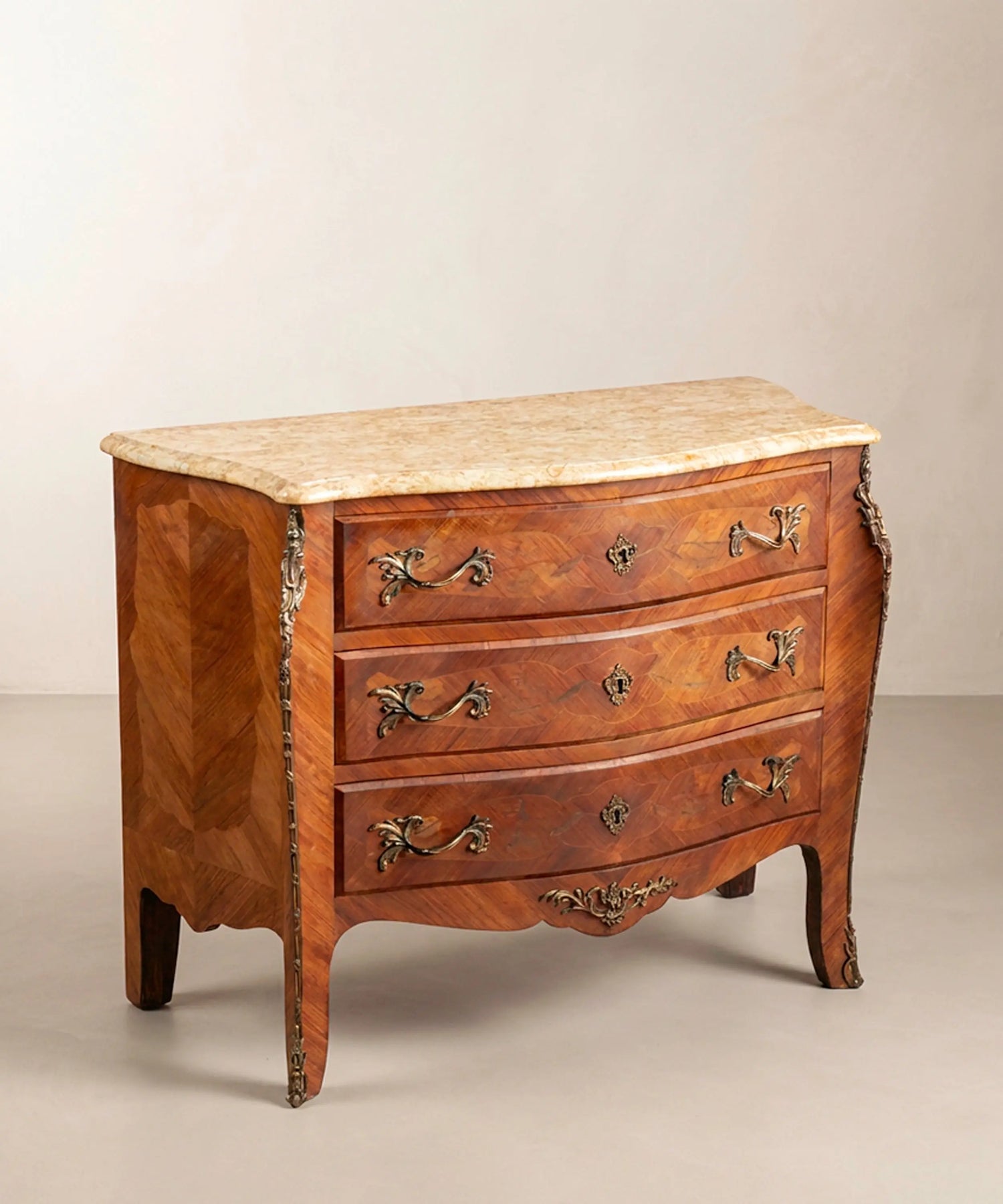 Cómoda panzuda estilo Luis XV de tres cajones con marquetería, bronces y tapa de mármol.