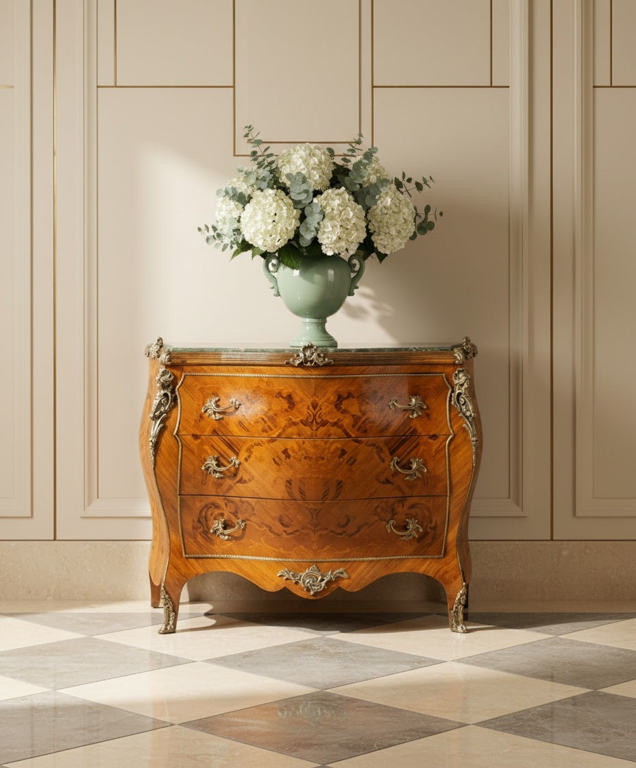 Cómoda francesa con jarrón de hortensias blancas en un salón de diseño neoclásico con molduras de pared.