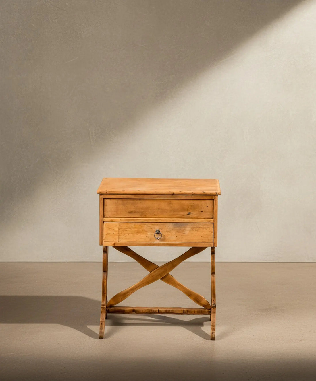 Mesa de costura antigua de madera abierta mostrando compartimentos interiores azul turquesa y cajón entreabierto sobre patas en X.