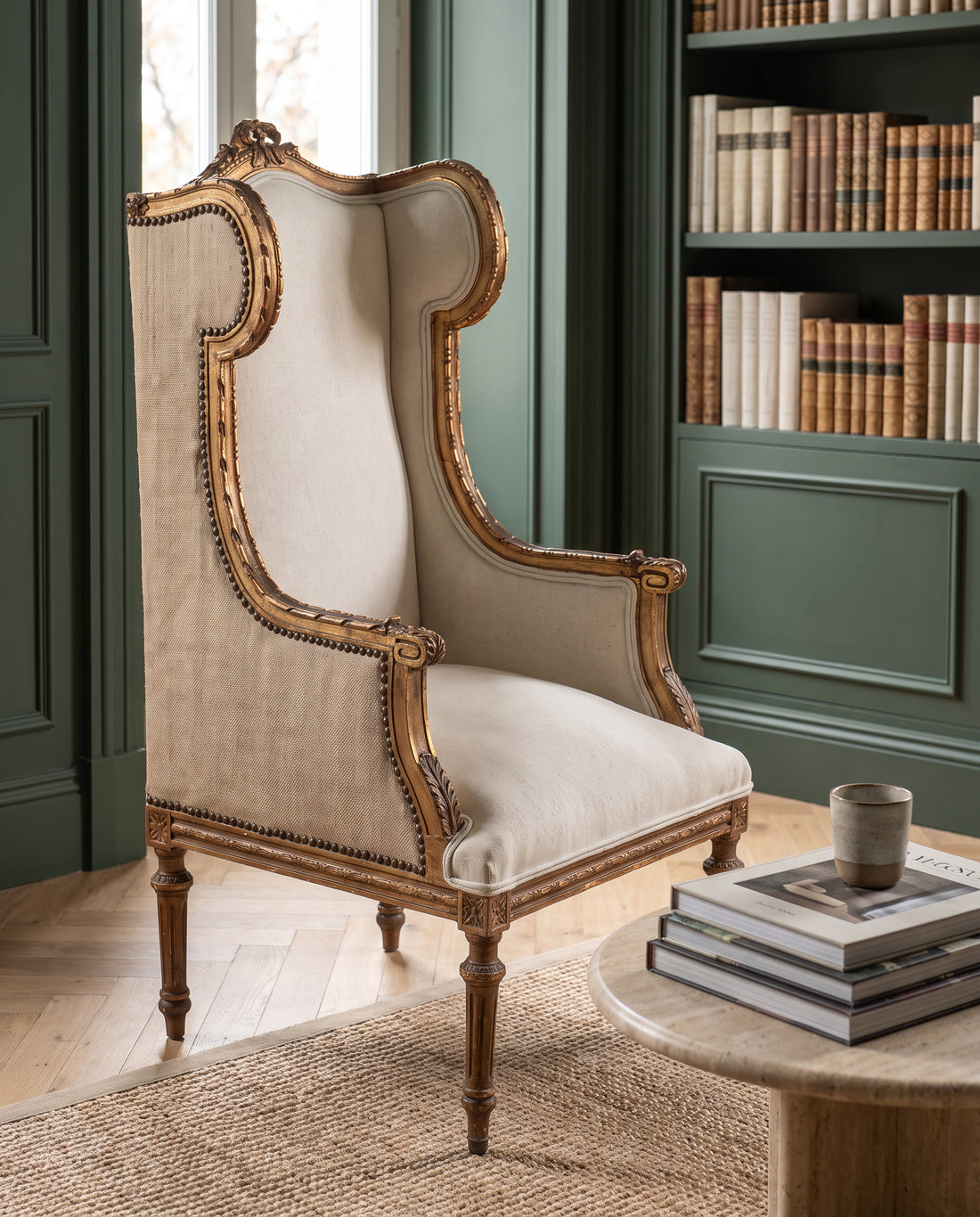 Sillón orejero antiguo dorado al pan de oro en biblioteca verde con estanterías — Antique Arte y Decoración