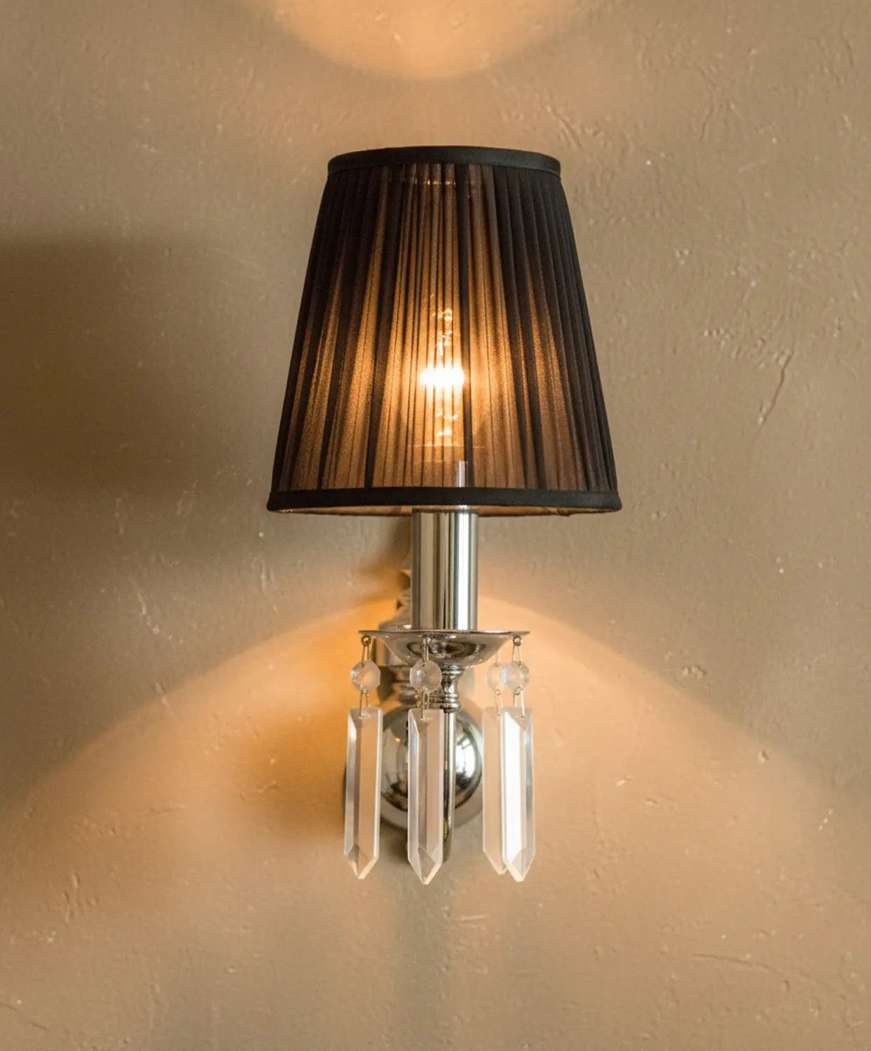 Vista de perfil de lámpara de pared con brazo curvo cromado y pantalla oscura.