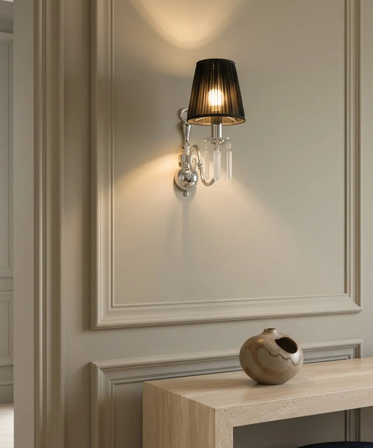 Aplique de pared encendido con pantalla cónica negra plisada y estructura plateada."